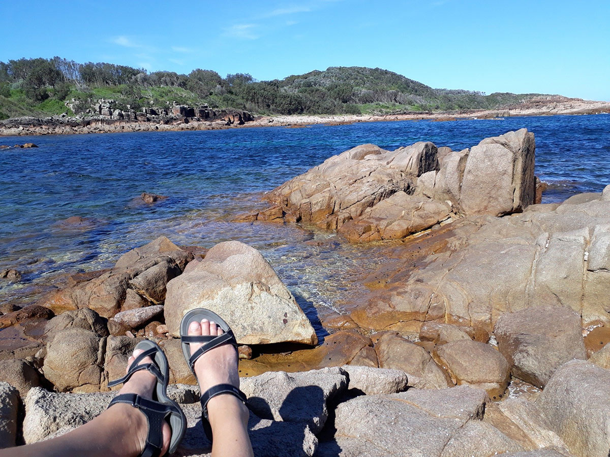 Photo of the tired feet of a hiker resting at the edge of a lake after a long hike